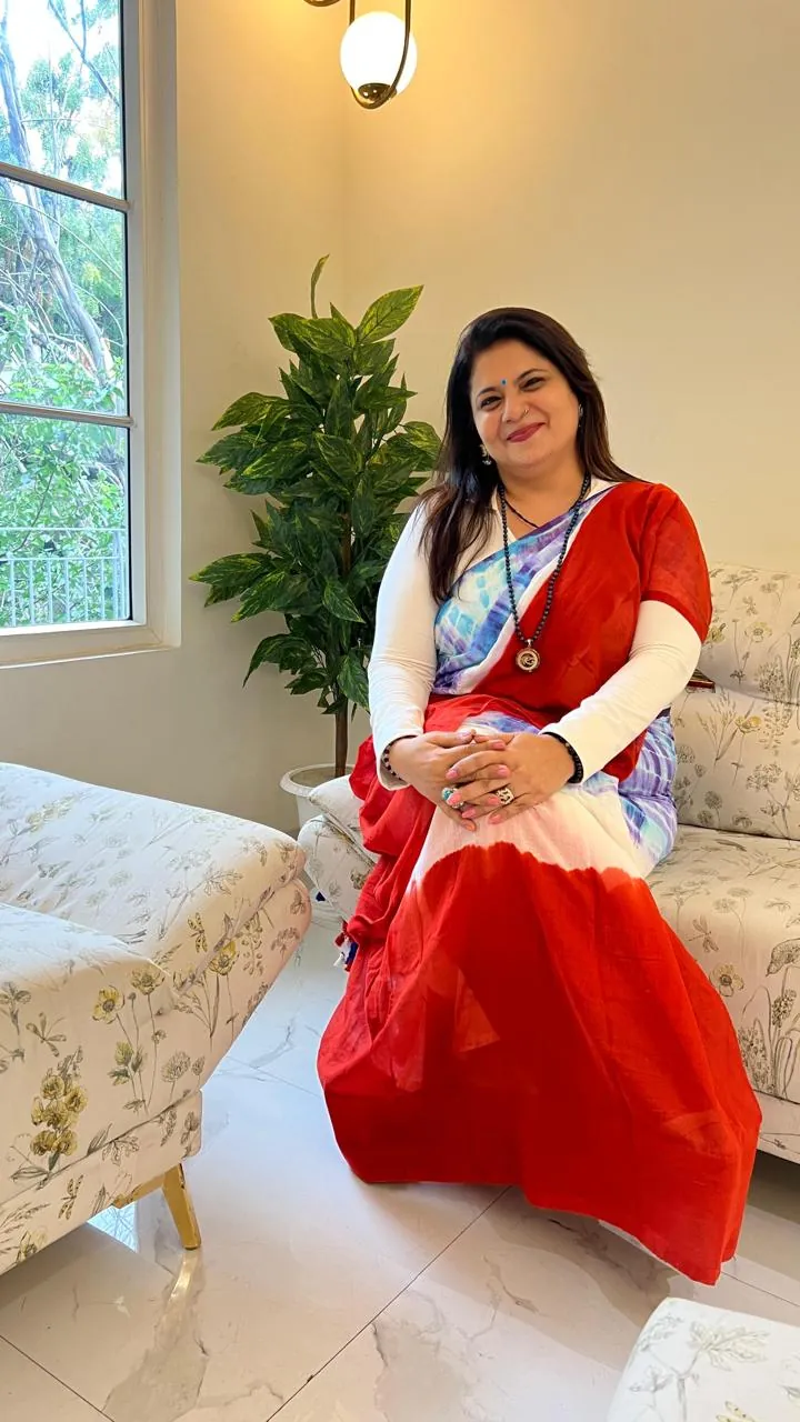 Sapnaa Khemani seated in her consulting room in a red and white tie-dye saree
