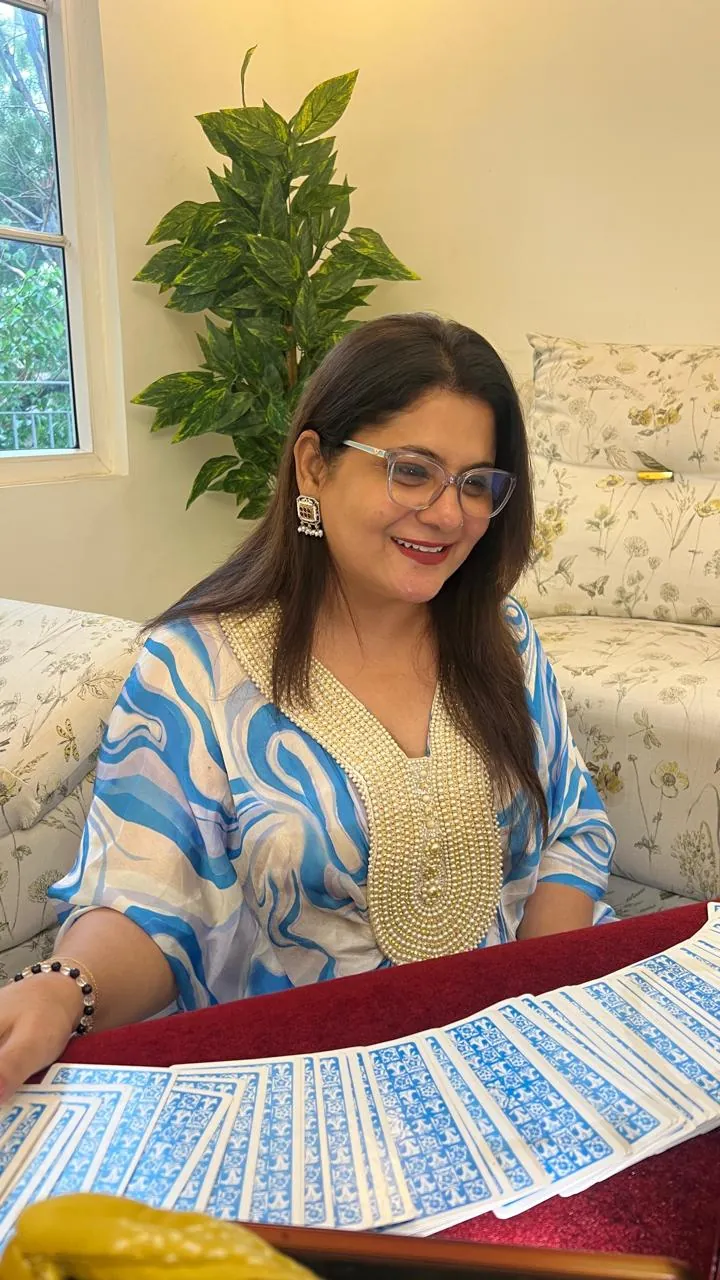 Sapnaa Khemani in a blue printed kurta and pearl necklace, reading at the card table